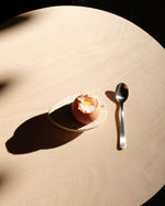 Eggshell on a plate with a spoon on a beige surface