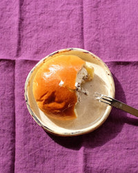 Plate with a partially eaten dessert on a purple textured surface