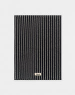 Black and white striped mat with 'Tekla' label on a light gray background