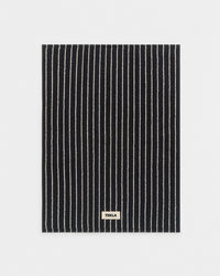 Black and white striped mat with 'Tekla' label on a light gray background
