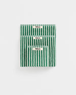 Three folded green and white striped cotton bath towels stacked vertically on a light gray background, each with a small white label reading TEKLA.