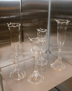 Set of four clear glass goblets on a reflective surface