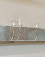 Three clear glass goblets on a reflective surface with a neutral background