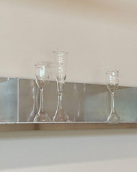 Three clear glass goblets on a reflective surface with a neutral background