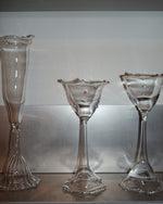 Three clear glass pieces on a reflective surface with a neutral background
