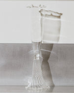 Clear glass vase with textured base on a reflective surface