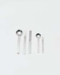 Set of silver cutlery including spoons and forks on a white background