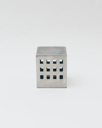 Metallic cube with square cutouts on a white background