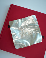 Silver earring set on a silver tray with a red background