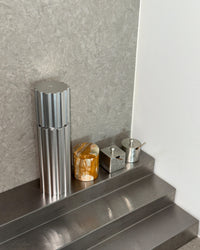 Metallic canister on a metallic surface with a neutral background