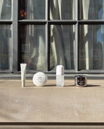 Skincare products on a ledge with a modern building in the background