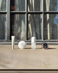 Skincare products on a ledge with a modern building in the background