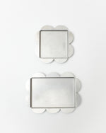 Two decorative trays with scalloped edges on a white background