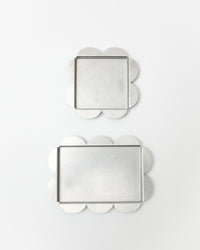 Two decorative trays with scalloped edges on a white background