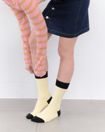 Person wearing pink striped tights and cream socks with black toes and cuffs on a white background