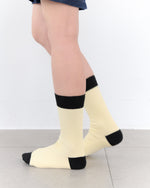 White socks with black toes and cuffs worn by a person on a light gray floor.