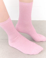 Pink socks worn on a light gray surface with a white background