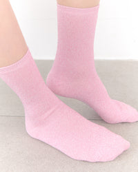 Pink socks worn on a light gray surface with a white background
