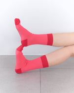 Person wearing bright pink socks with red accents on a light gray floor.