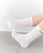 White textured socks worn by a person on a light gray floor.