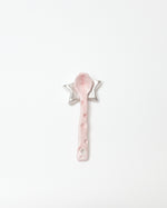 Pink spoon with decorative stars on a white background
