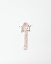 Pink spoon with decorative stars on a white background