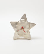 Star-shaped clock with a metallic finish on a white background