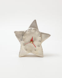 Star-shaped clock with a metallic finish on a white background