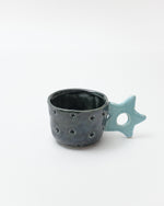 Ceramic cup with star-shaped handle on a white background