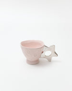 Pink ceramic cup with star design on a white background