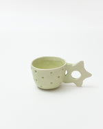 Green ceramic cup with star-shaped handle on a white background