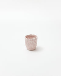 Pink textured ceramic cup on a white background