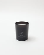 Black candle in a cylindrical container on a white background