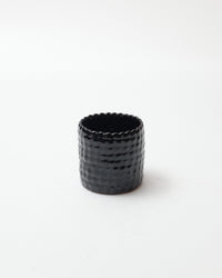 Black textured ceramic cup on a white background