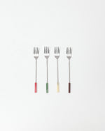 Four forks with colored handles on a white background