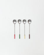 Four spoons with colorful handles on a white background