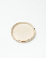 Round ceramic plate with a textured edge on a white background