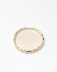 Round ceramic plate with a textured edge on a white background