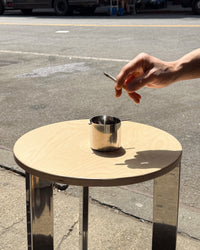 Hand lighting a cigarette over a small round table on a street.