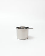 Small stainless steel pot with a handle on a white background