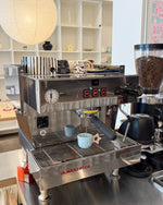 Espresso machine in a coffee shop with a cup of coffee being brewed.