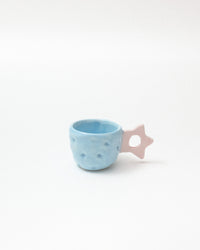 Blue ceramic cup with a pink star-shaped handle on a white background