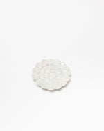 Round white stone coaster on a light beige background