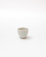 Small ceramic cup with textured surface on a white background