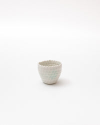 Small ceramic cup with textured surface on a white background