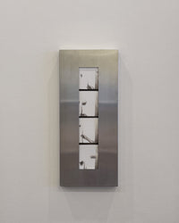 Metallic wall frame with four rectangular panels on a white wall