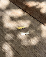 Two small bookmarks, one gold and one silver, on a wooden surface with shadows.