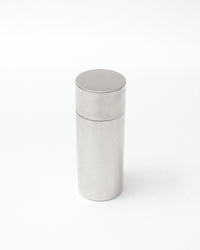 A minimalist, brushed stainless steel cylindrical container with a matching screw-top lid, shown on a seamless white background.