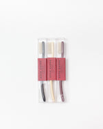 Three Acca Kappa toothbrushes in a clear plastic package with pink paper bands, shown on a plain white background.