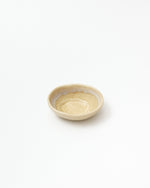A small handmade ceramic bowl with a textured, speckled beige exterior and a smooth, slightly scalloped off-white interior, photographed on a seamless white background.